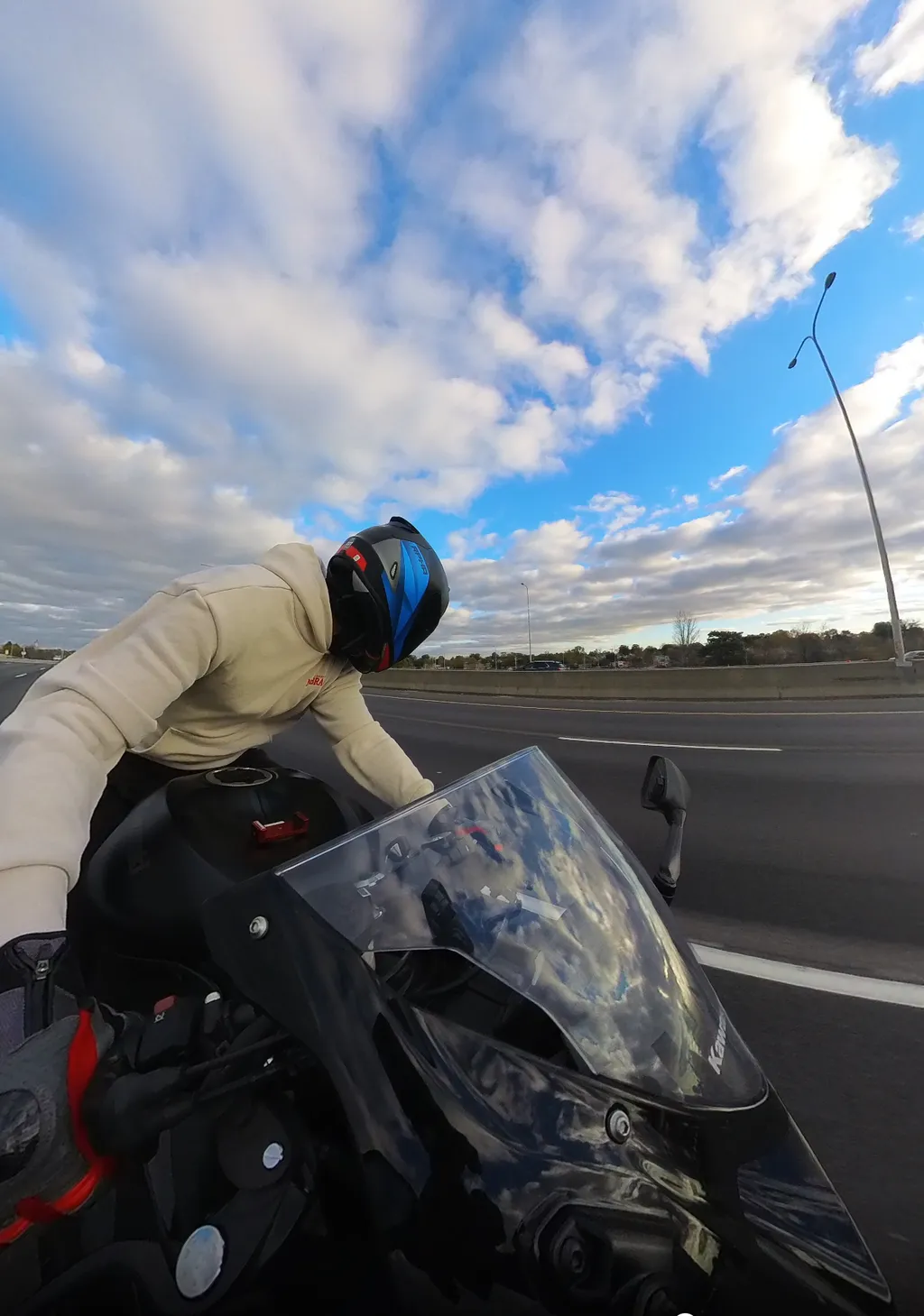 A helmeted motorcyclist in Omaha, Nebraska, with clouds reflected in the motorcycle windshield.
