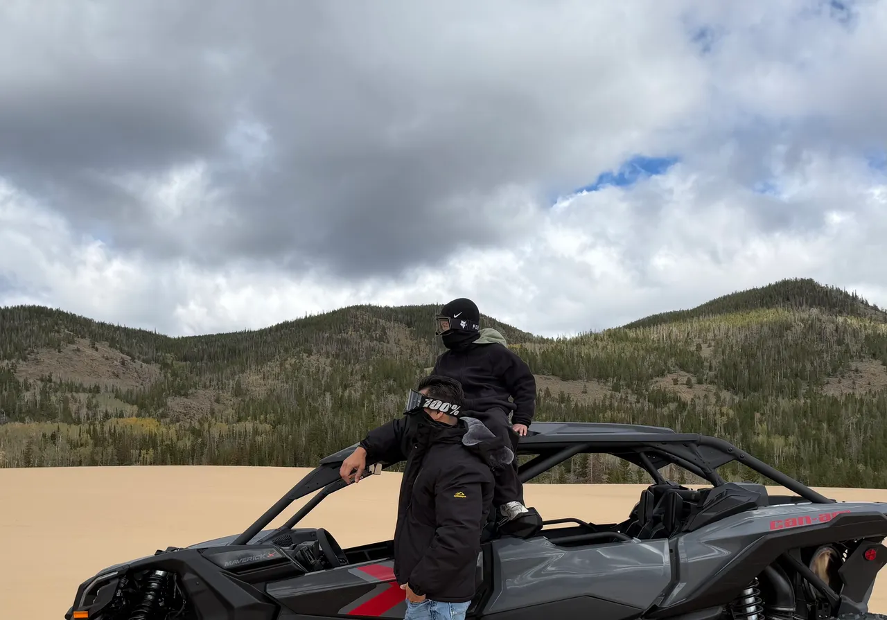 An outdoor outing at North Sand Hills, Colorado, with an off-road vehicle, sand dunes, forest, and mountains.